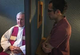 A Catholic priest hearing confession from a man in a confessional